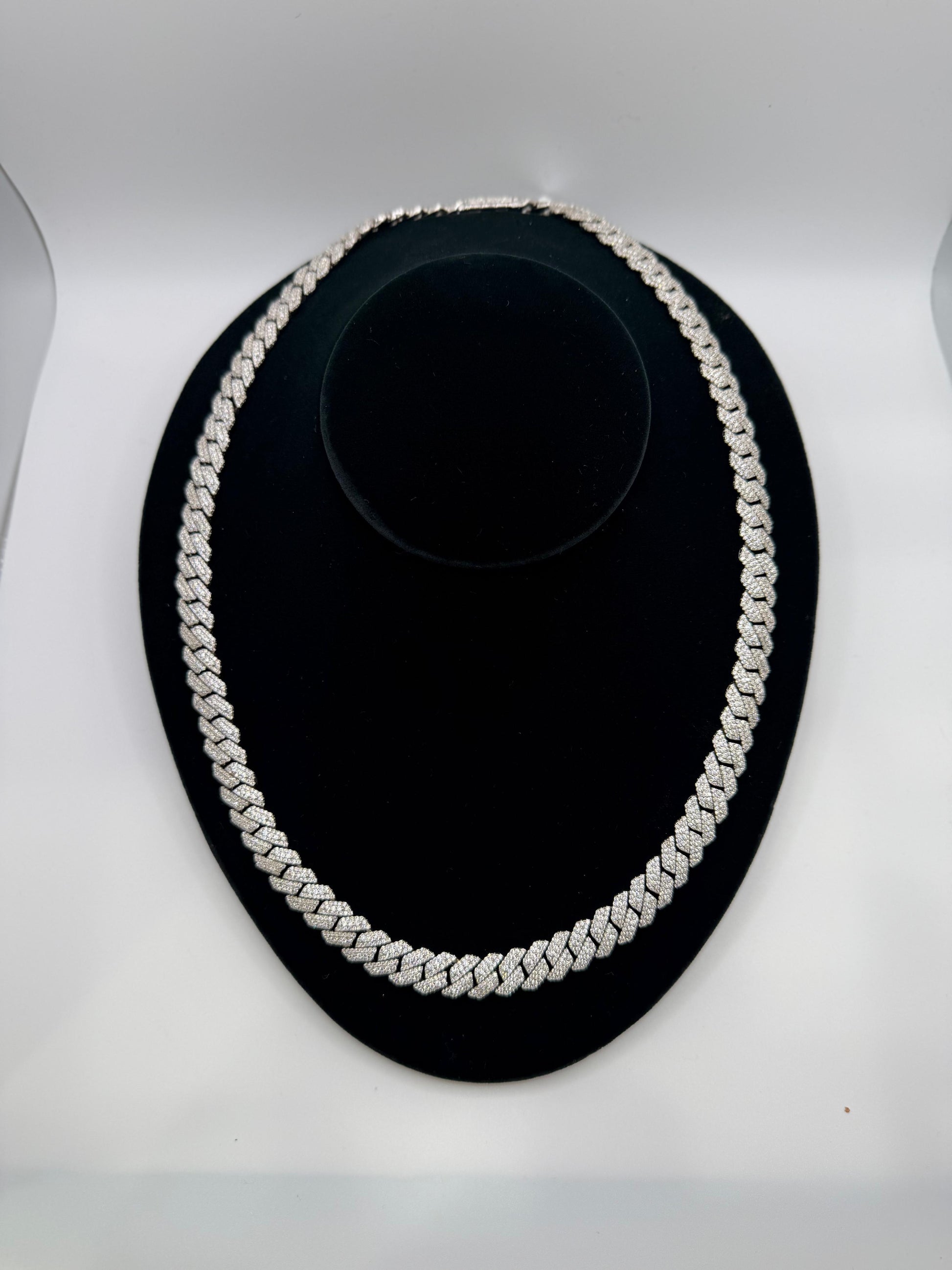 Silver chain necklace on a black stand against a white background