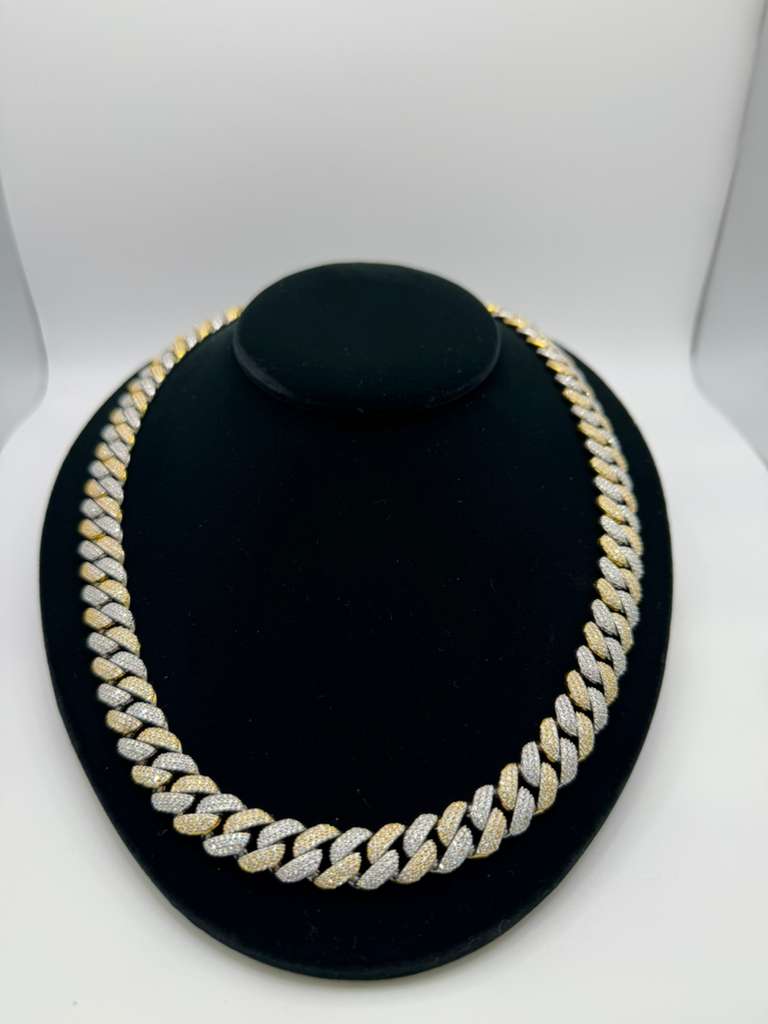 Gold and silver chain necklace on a black stand against a white background