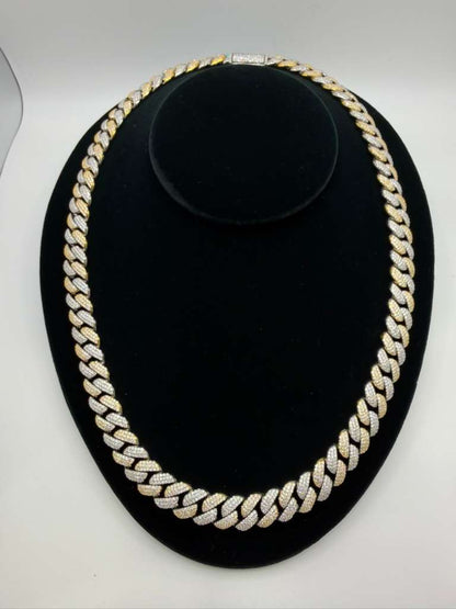 Gold chain necklace on a black stand with a white background